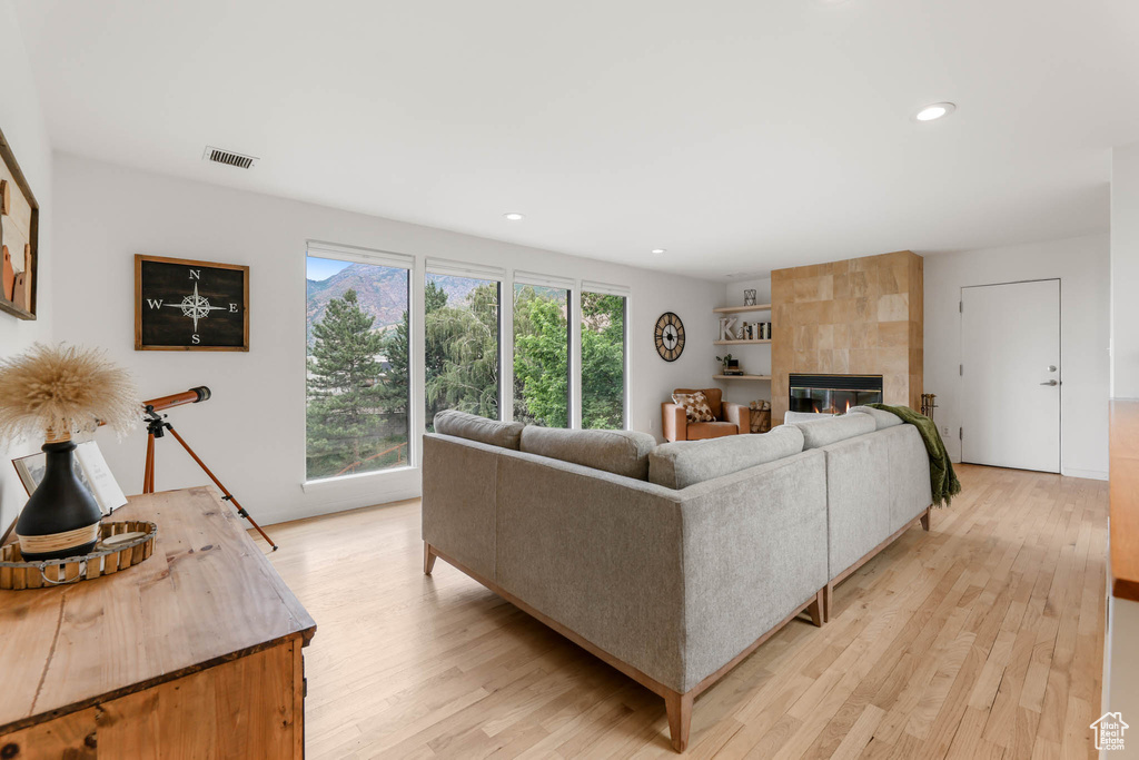Living room featuring light wood-style floors, recessed lighting, and a tiled fireplace
