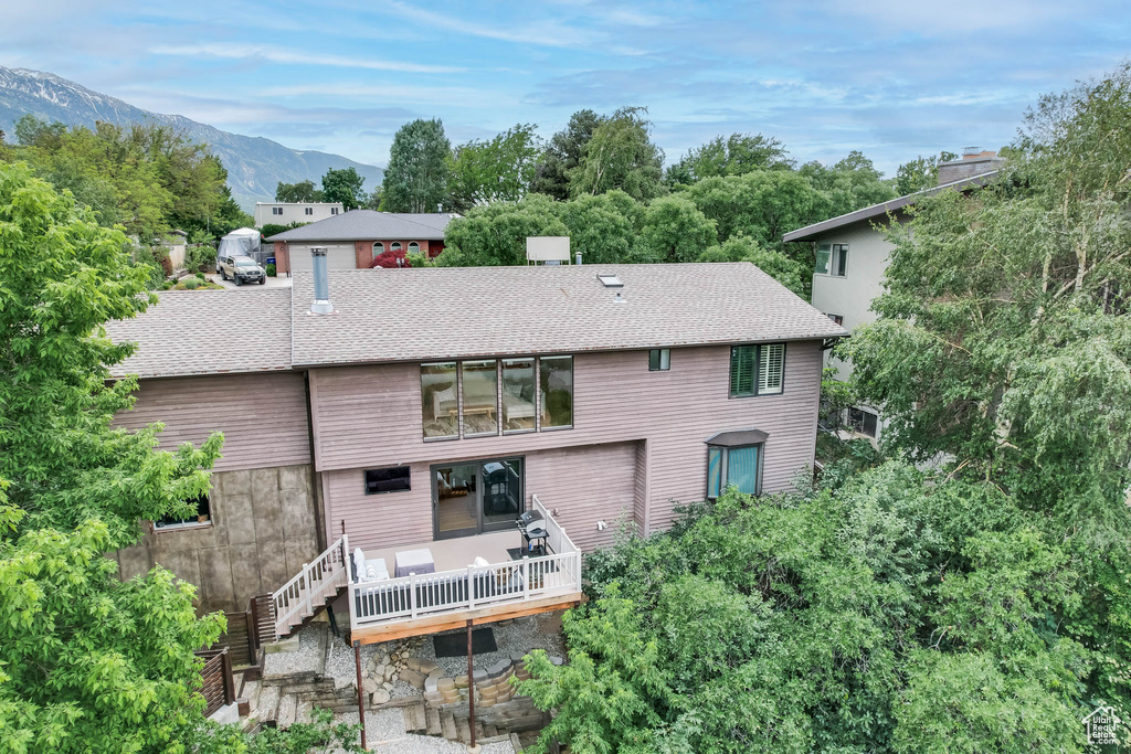 Rear view of house with a deck with mountain view, roof with shingles, and stairway