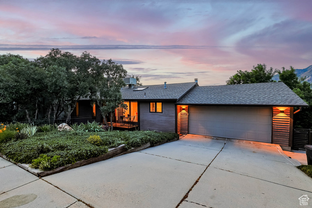 View of front of home with concrete driveway, a shingled roof, and an attached garage