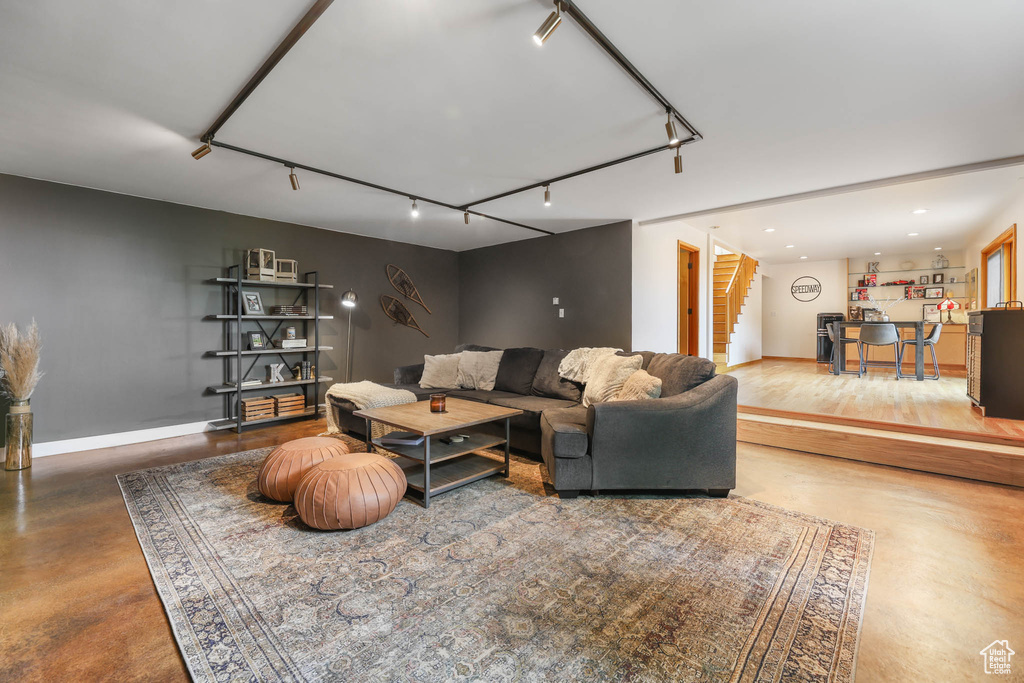 Living room featuring track lighting, stairway, and finished concrete flooring