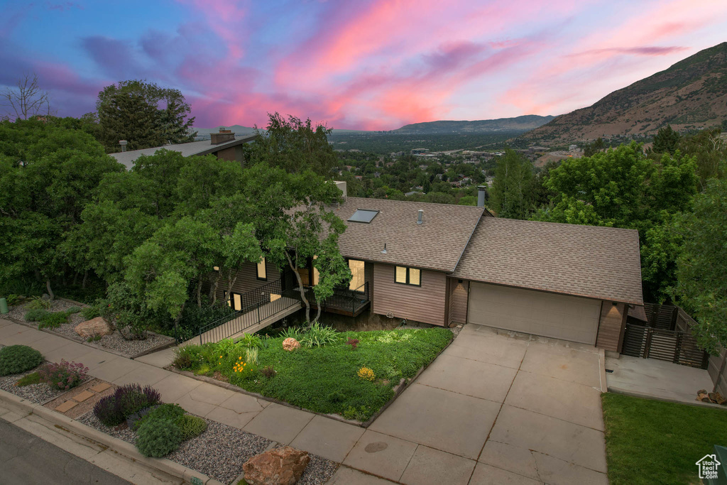 View of front of property featuring driveway, an attached garage, roof with shingles, and a mountain view