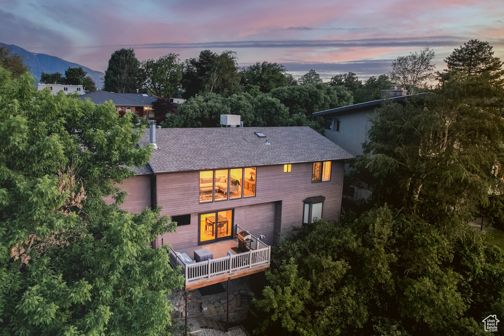 Back of property at dusk featuring a shingled roof and a mountain view