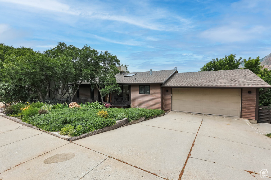 View of front of property featuring driveway, a garage, and roof with shingles