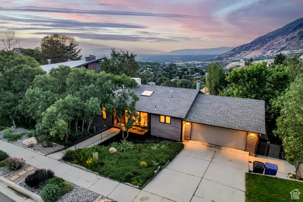 View of front facade with a shingled roof, driveway, an attached garage, and a mountain view