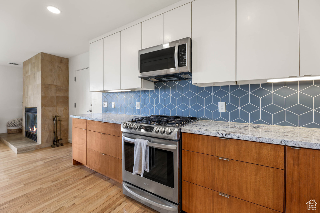 Kitchen featuring stainless steel appliances, light wood-style floors, light stone counters, and modern cabinets