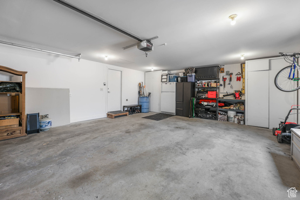 Garage featuring freestanding refrigerator and a garage door opener