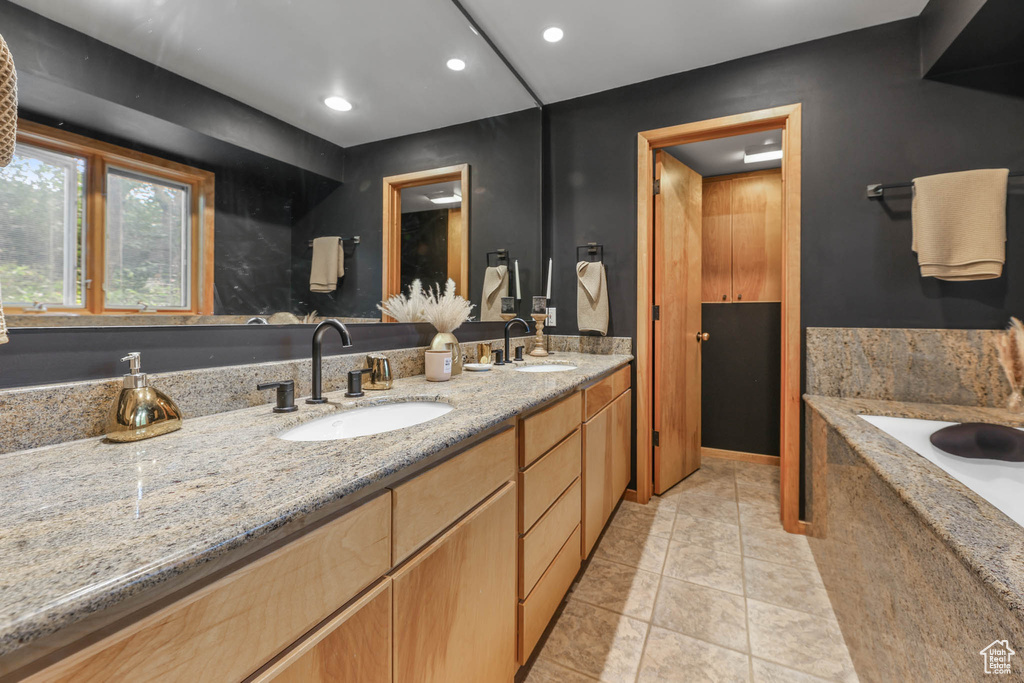Bathroom with double vanity, a tub with marble appearance, recessed lighting, and tile patterned flooring