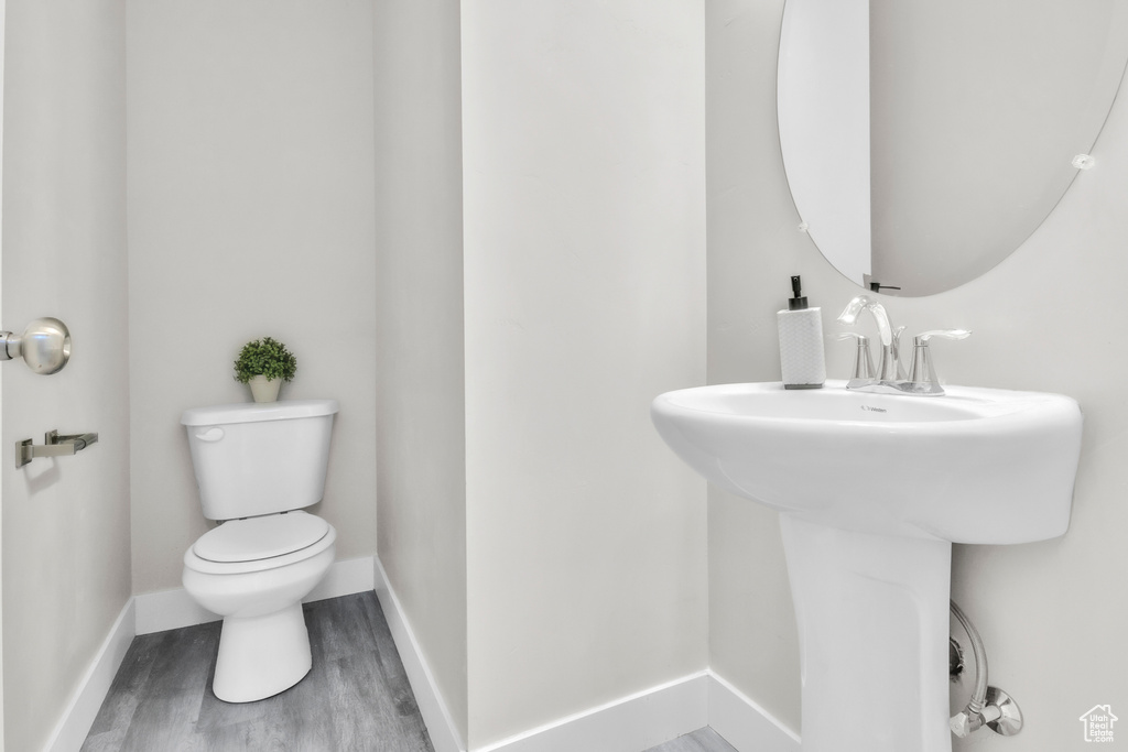 Half bathroom with toilet and wood finished floors
