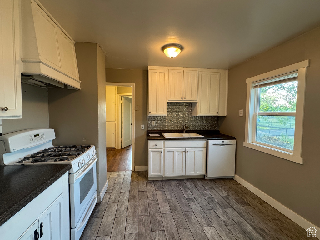 Kitchen featuring white appliances, dark wood-type flooring, dark countertops, and custom range hood
