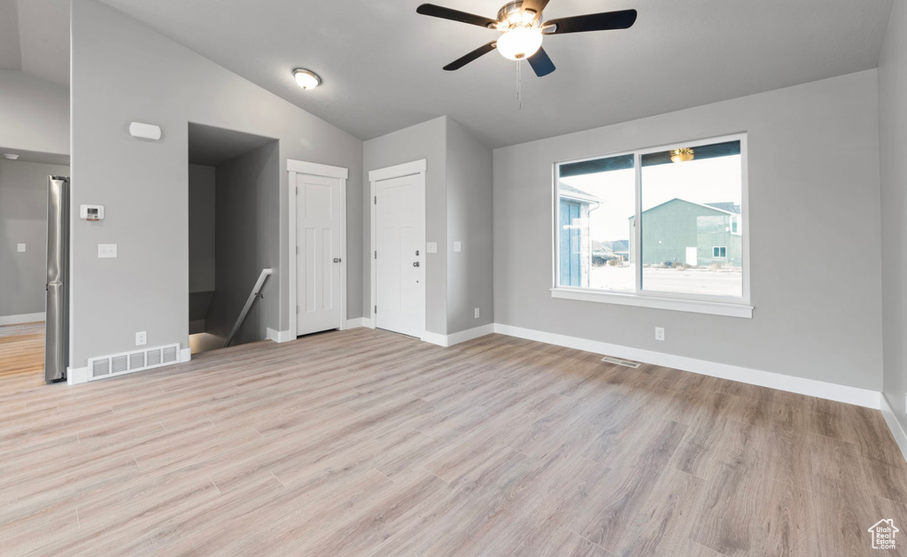 Unfurnished living room featuring vaulted ceiling, ceiling fan, and light wood-style floors