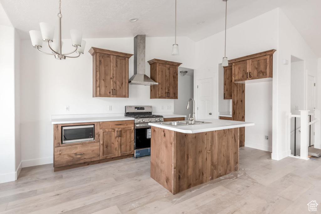 Kitchen with appliances with stainless steel finishes, wall chimney range hood, lofted ceiling, brown cabinetry, and a center island with sink