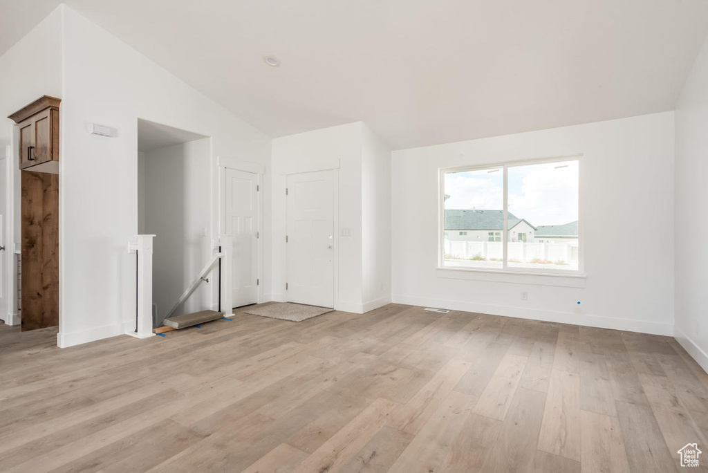 Unfurnished living room with vaulted ceiling and light wood-type flooring
