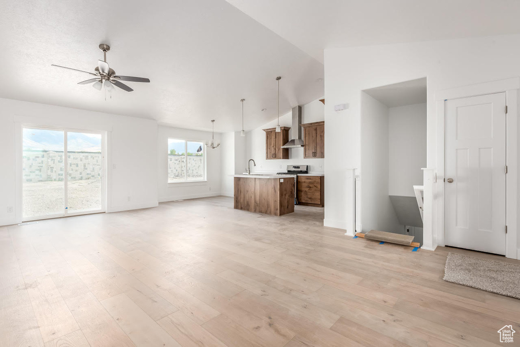 Unfurnished living room with ceiling fan, vaulted ceiling, and light wood-type flooring