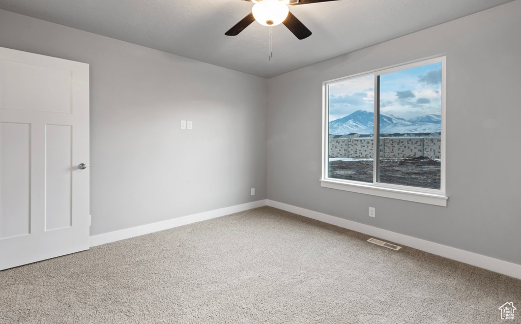 Carpeted spare room featuring ceiling fan and baseboards
