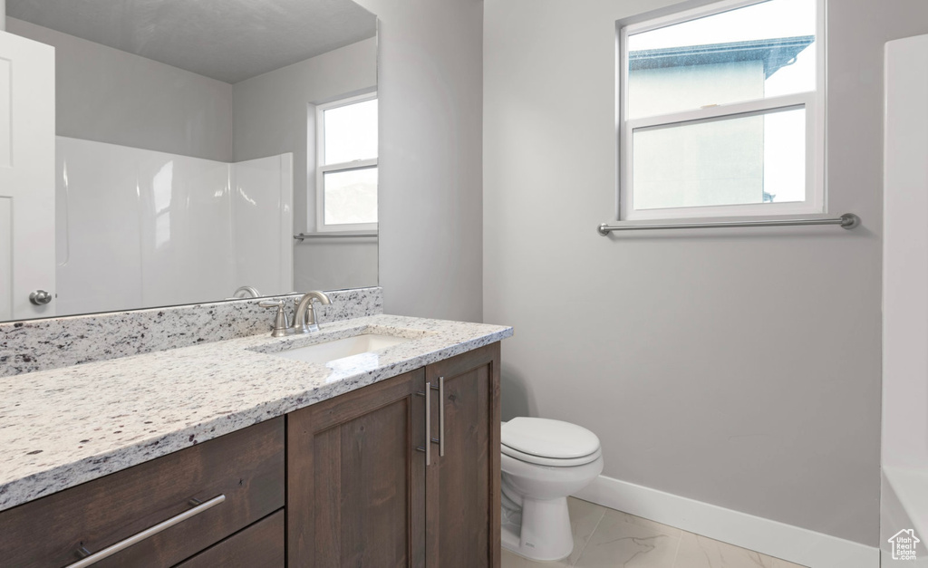 Full bath with marble look tile flooring, vanity, and a shower