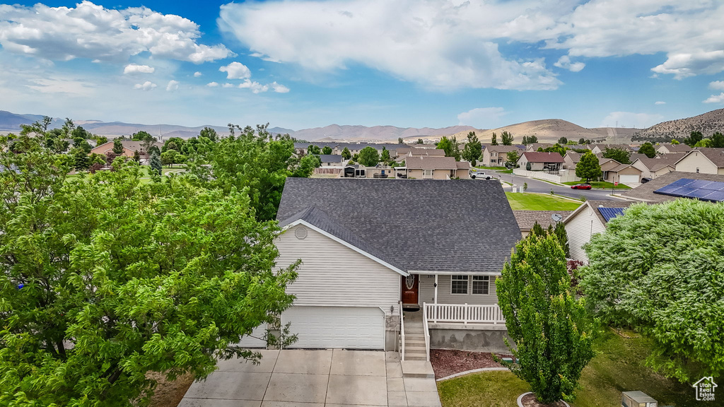 View of front of house with concrete driveway, a shingled roof, a mountain view, a garage, and a residential view