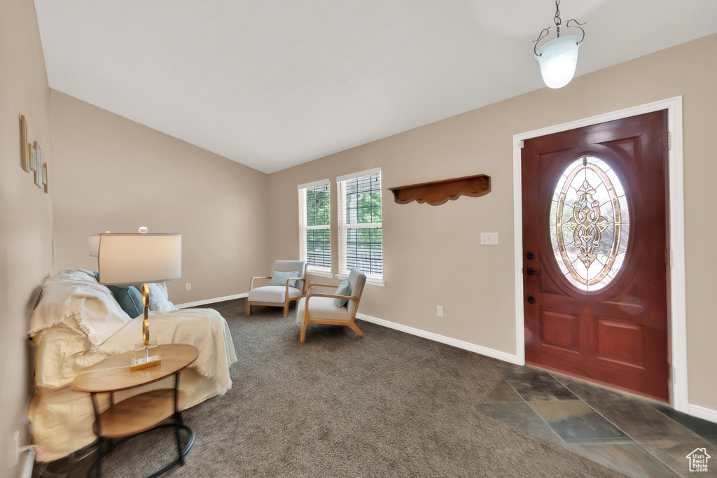 Entryway featuring lofted ceiling and dark colored carpet