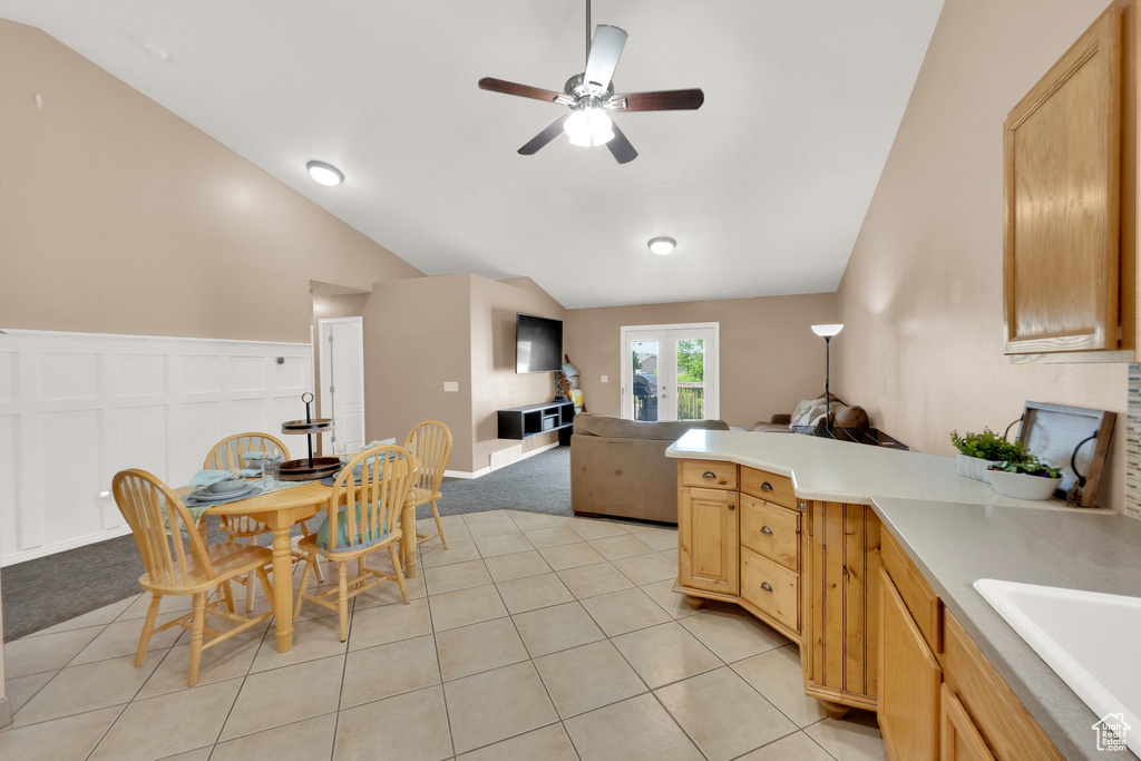 Kitchen with lofted ceiling, a peninsula, ceiling fan, open floor plan, and light countertops