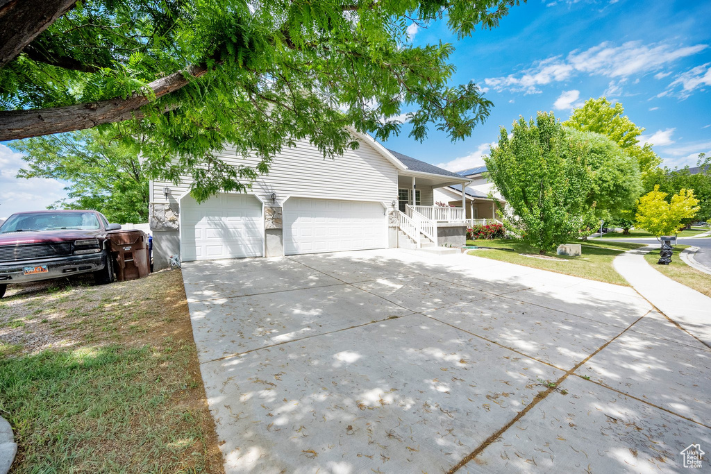 View of front facade with concrete driveway, a porch, a front yard, and a garage