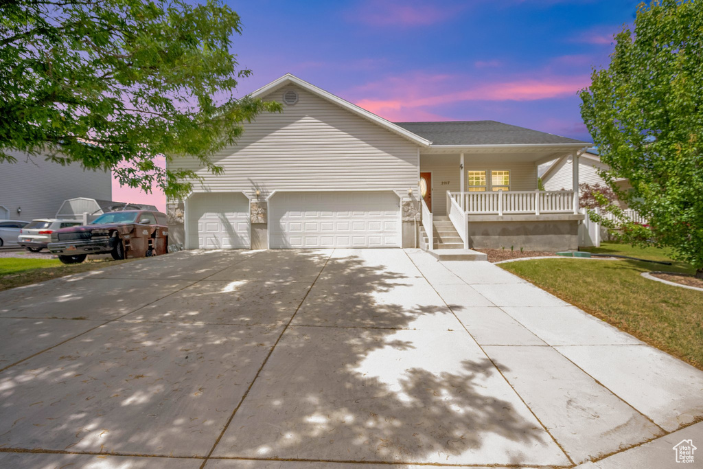 Ranch-style home featuring covered porch, driveway, a garage, and a front lawn