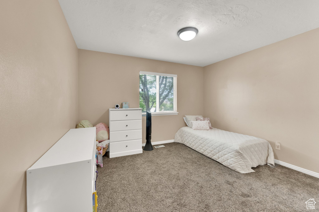 Bedroom featuring dark carpet and baseboards