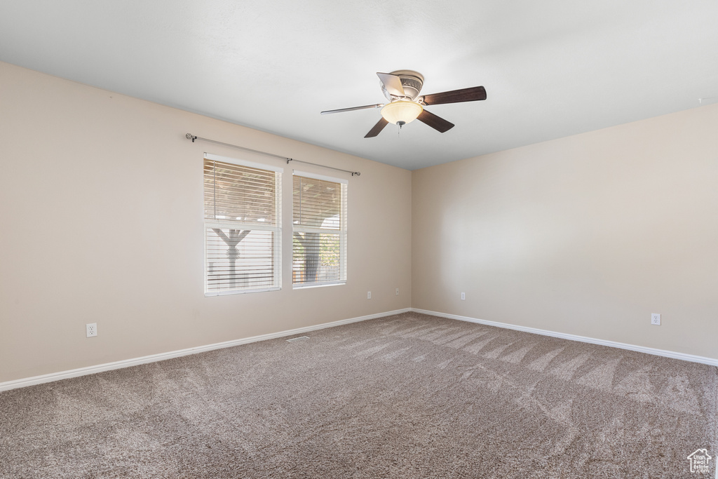Empty room featuring a ceiling fan and carpet floors