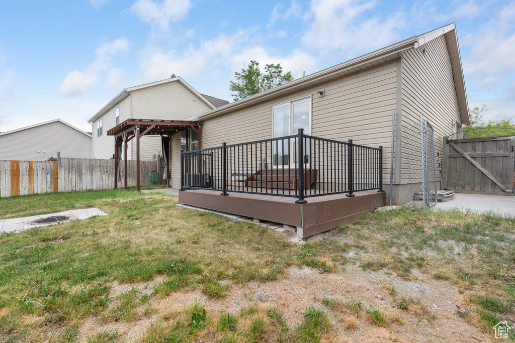 Rear view of house featuring a wooden deck, a fenced backyard, and a gate