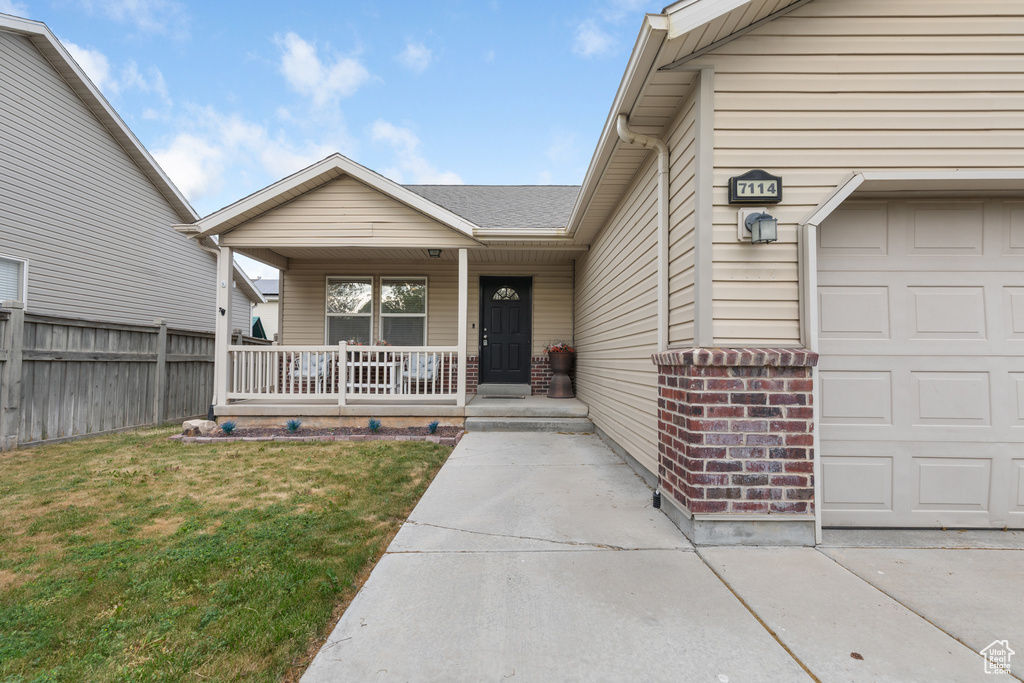 Entrance to property with covered porch, an attached garage, and a shingled roof