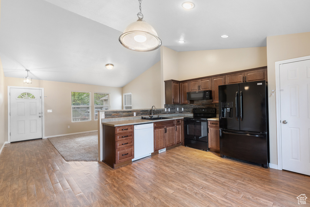 Kitchen featuring black appliances, light wood-type flooring, a peninsula, backsplash, and recessed lighting