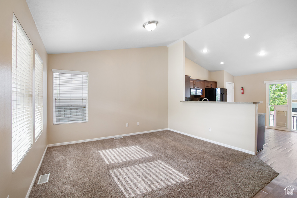 Unfurnished living room featuring lofted ceiling, recessed lighting, and wood finished floors