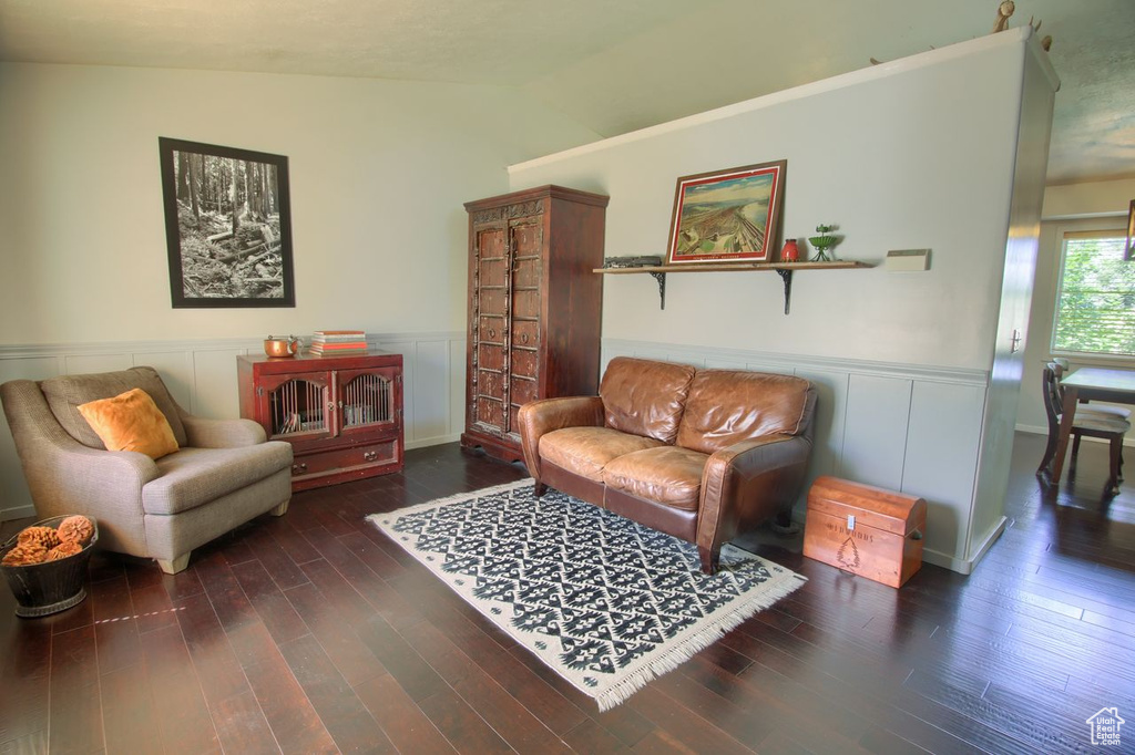 Sitting room featuring wainscoting, vaulted ceiling, and wood finished floors
