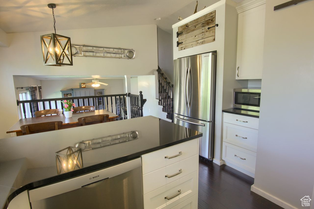 Kitchen featuring stainless steel appliances, dark wood-style flooring, dark countertops, and white cabinets