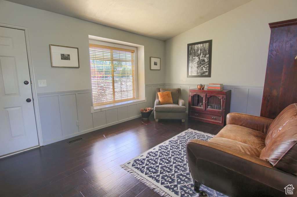 Living area with wainscoting, wood-type flooring, and lofted ceiling