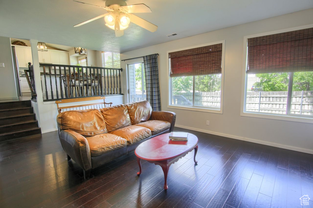 Living room featuring plenty of natural light, a ceiling fan, wood finished floors, and stairs