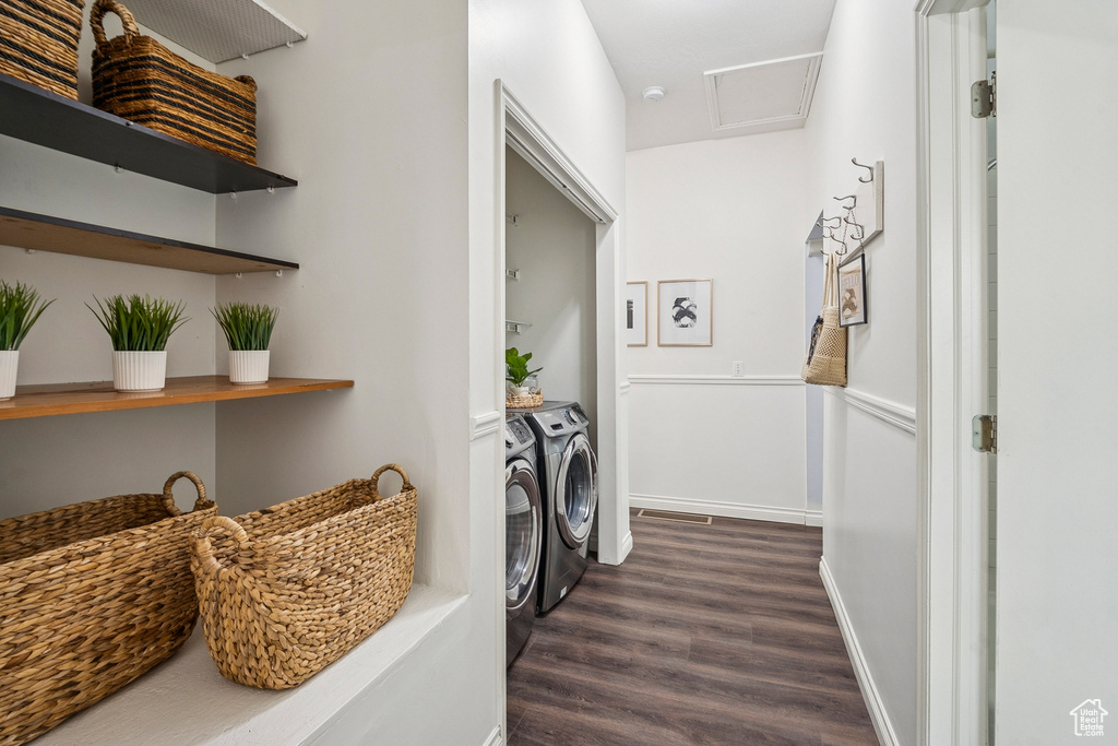 Washroom with washing machine and dryer and dark wood-type flooring