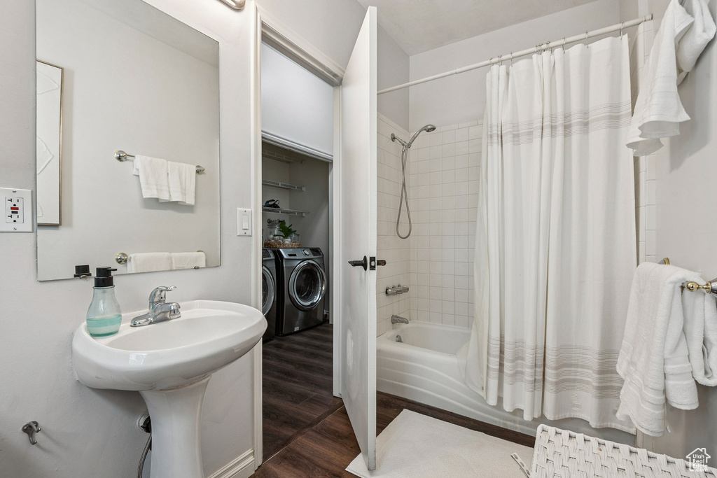 Bathroom with washing machine and dryer, wood finished floors, and shower / tub combo