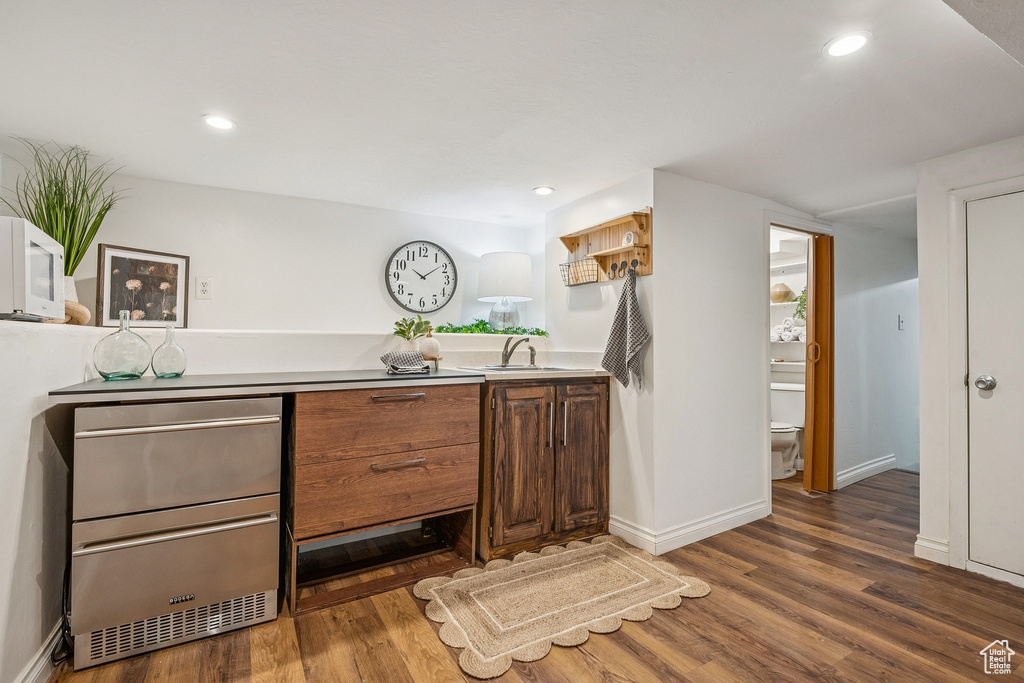 Kitchen with white microwave, wood finished floors, light countertops, and recessed lighting