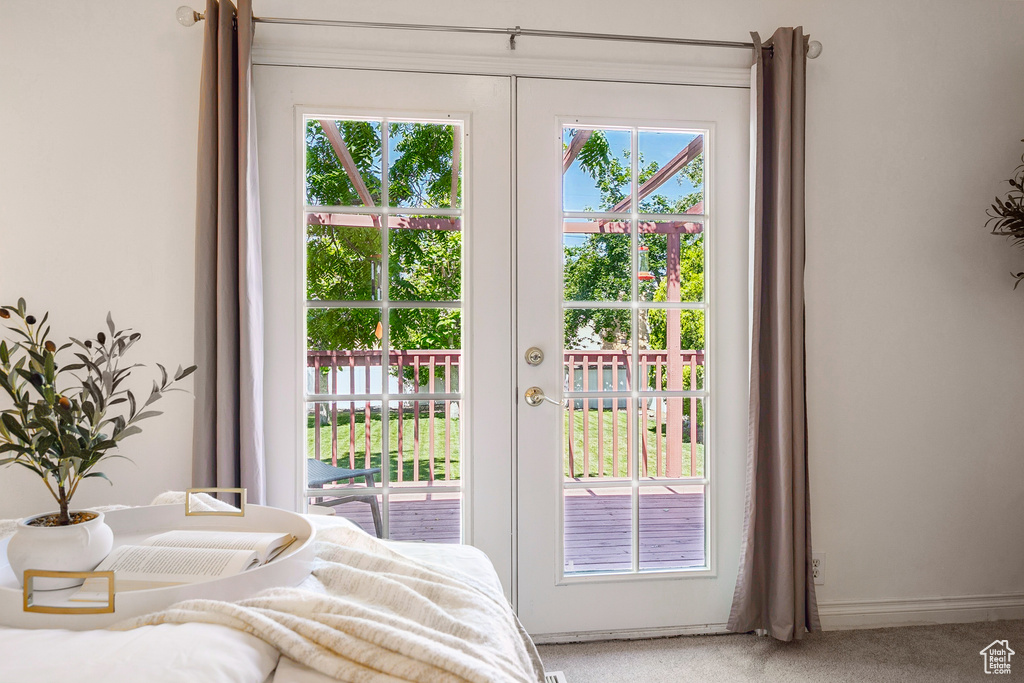 Bedroom featuring access to exterior, light colored carpet, french doors, and multiple windows