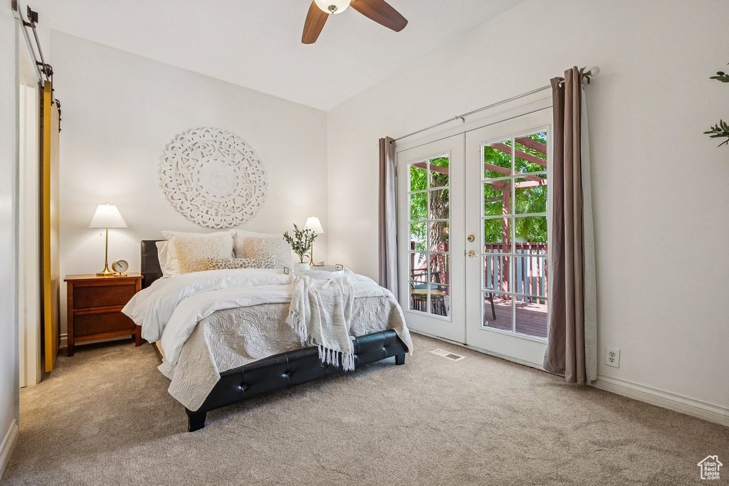 Carpeted bedroom featuring access to exterior, a barn door, french doors, and a ceiling fan