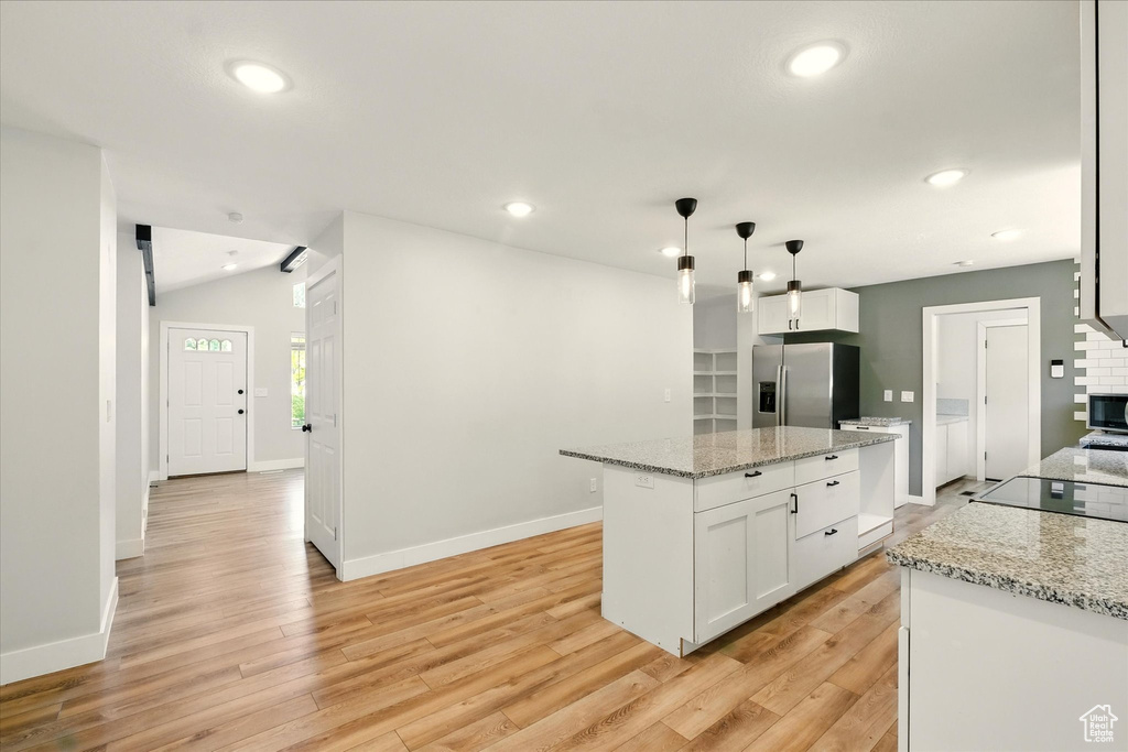 Kitchen featuring stainless steel refrigerator with ice dispenser, white cabinetry, light wood-style floors, recessed lighting, and a center island