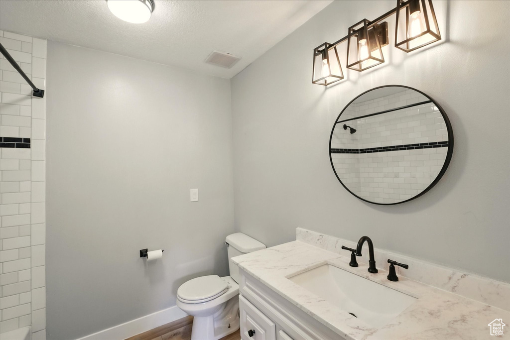 Full bathroom featuring vanity, a shower, wood finished floors, and a textured ceiling