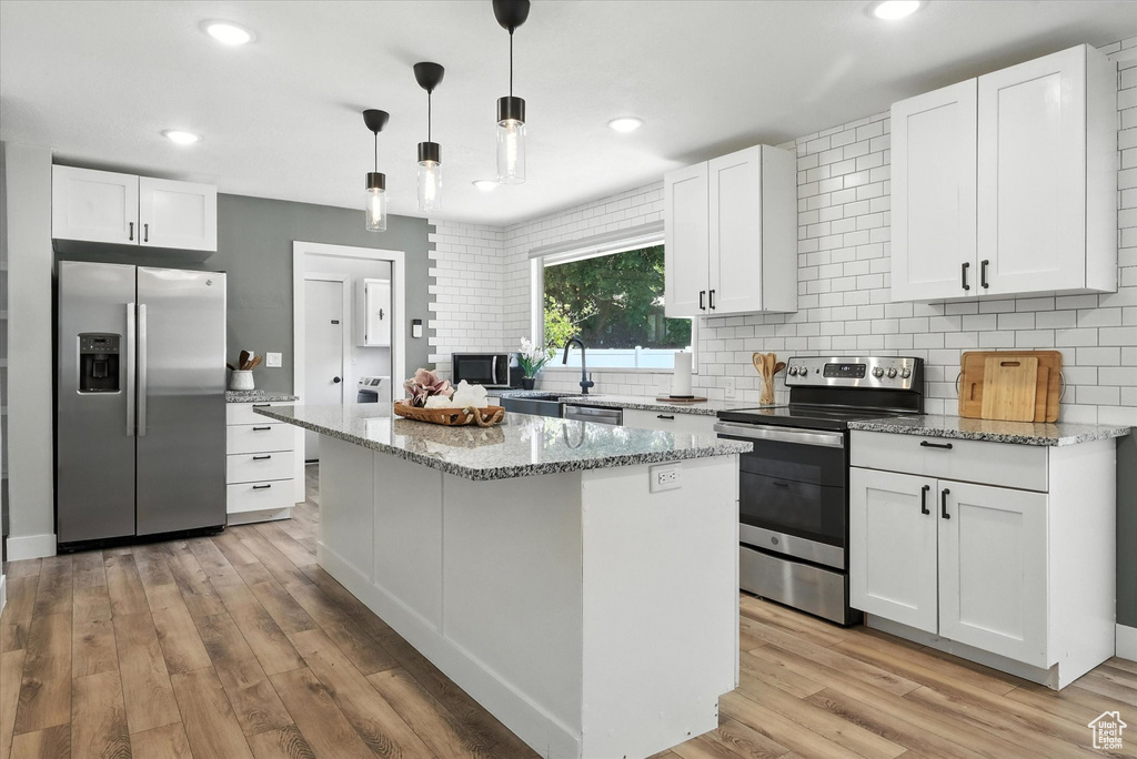 Kitchen featuring appliances with stainless steel finishes, tasteful backsplash, white cabinets, a kitchen island, and recessed lighting