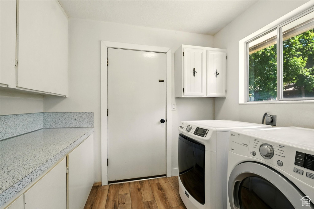 Laundry room with cabinet space, wood finished floors, and washer and clothes dryer