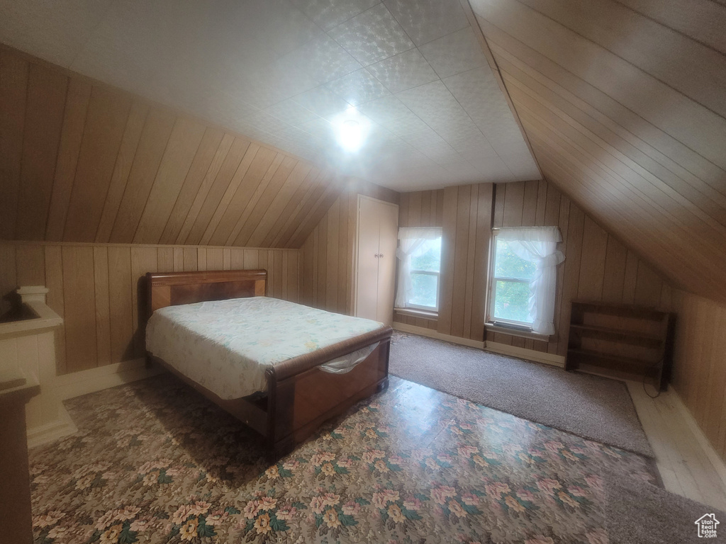 Bedroom with vaulted ceiling and wood walls