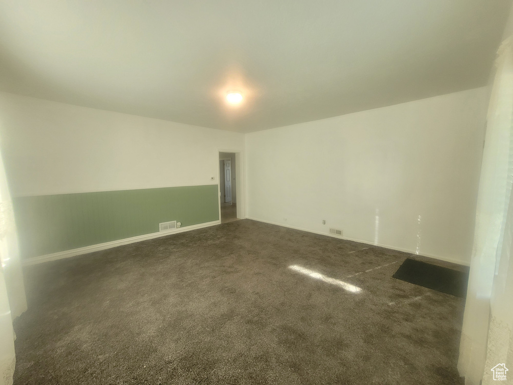 Unfurnished room with dark carpet and baseboards