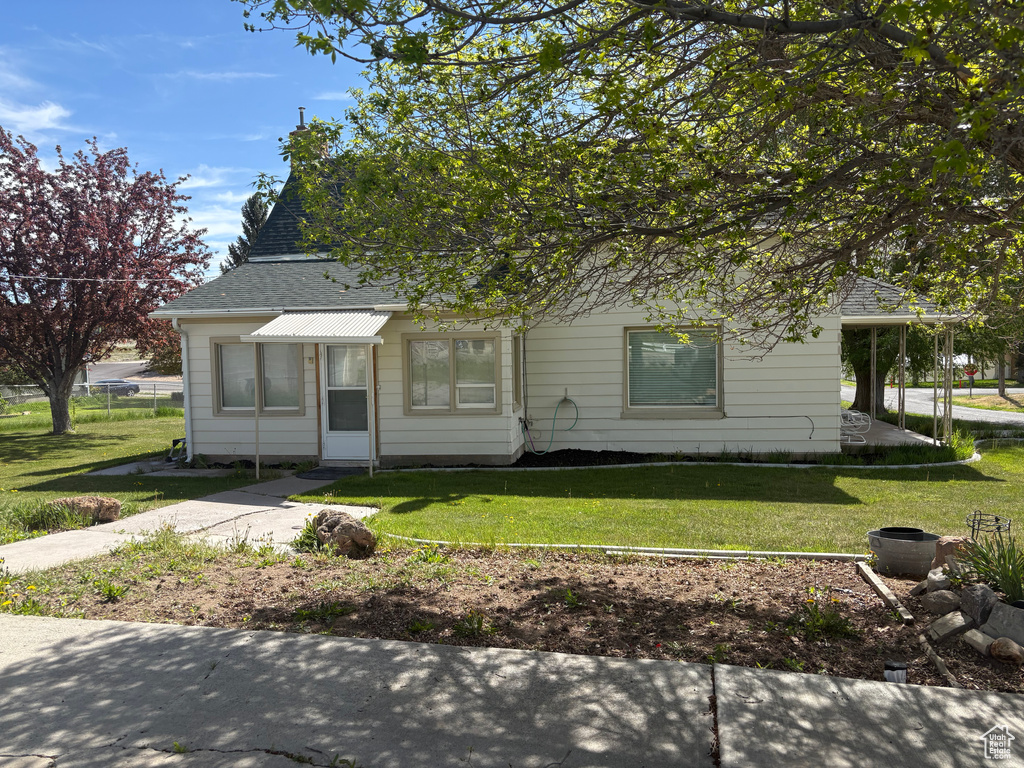 View of front facade featuring a front lawn and a shingled roof
