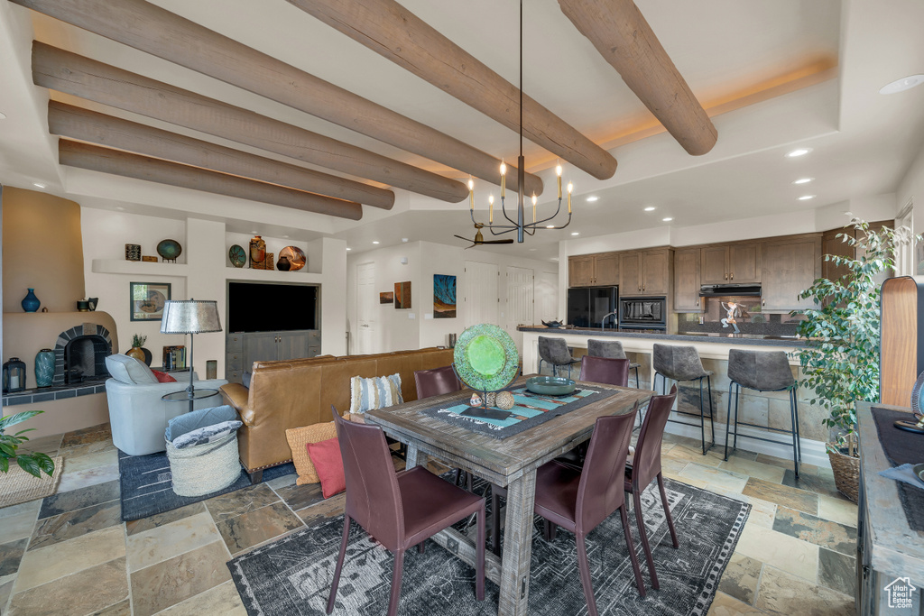 Dining room featuring stone tile flooring, a chandelier, recessed lighting, and beam ceiling