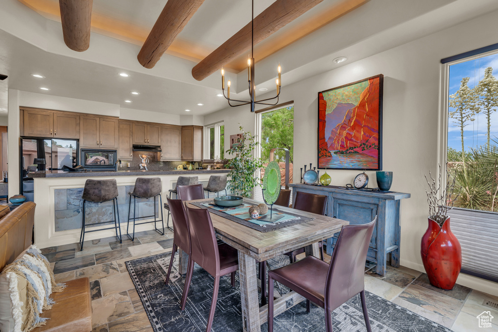Dining room with beamed ceiling, recessed lighting, stone tile floors, and a chandelier