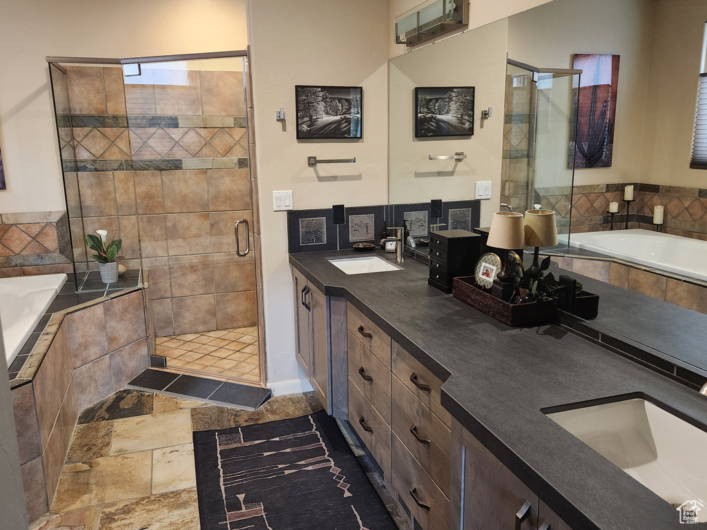 Bathroom with double vanity, a bath, a shower stall, and stone finish floors