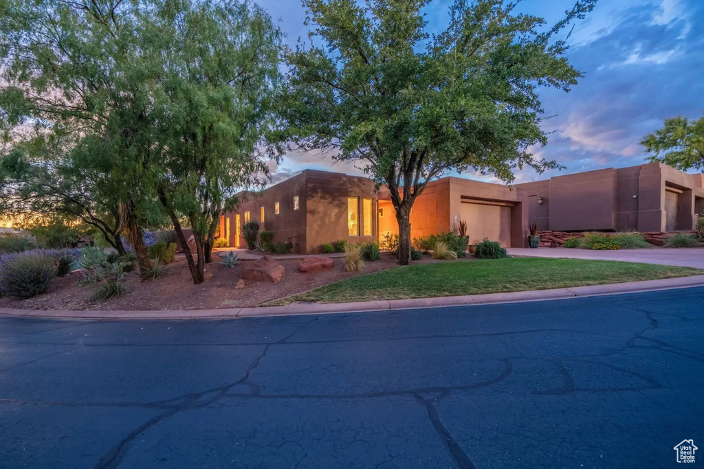 Pueblo-style house with an attached garage, concrete driveway, and stucco siding